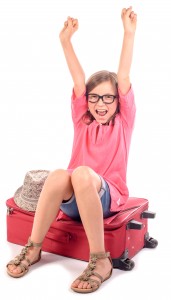girl sitting on a suitcase is happy to go on holiday